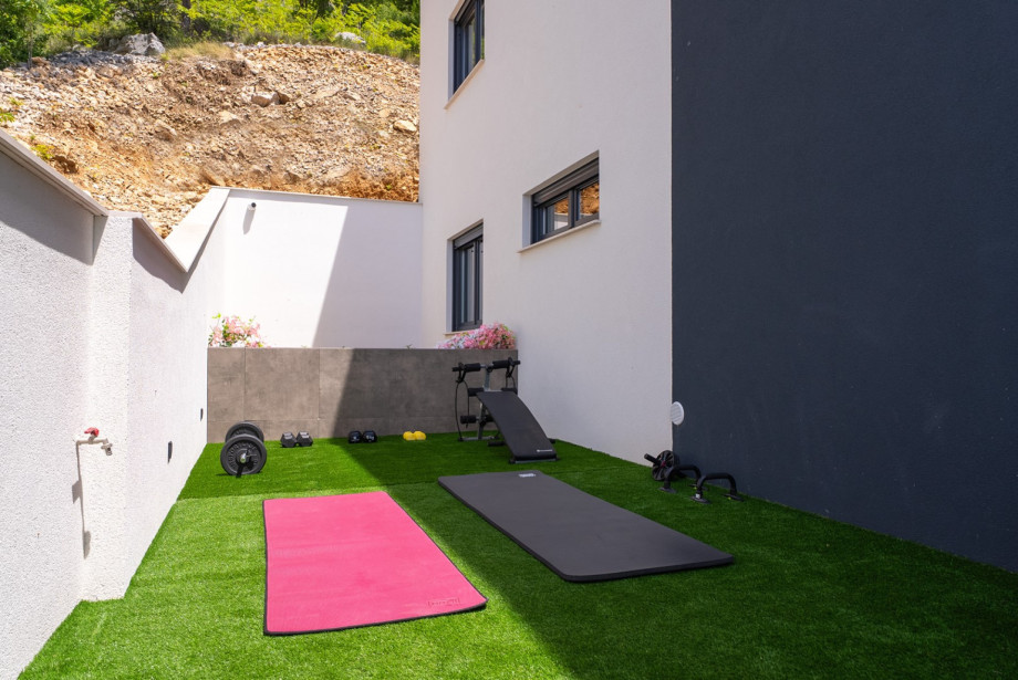 The grass plot includes fitness equipment and a small playground for children, ensuring fun for all ages