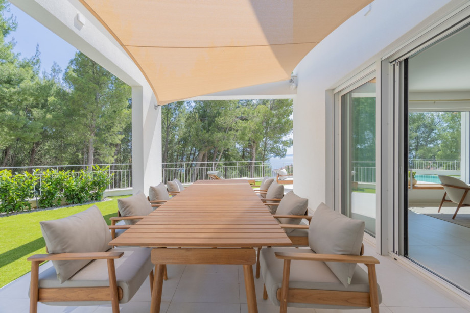 Große Glastüren lassen natürliches Licht herein und bieten einen entspannenden Blick auf den Pool, das Grün und das Meer.