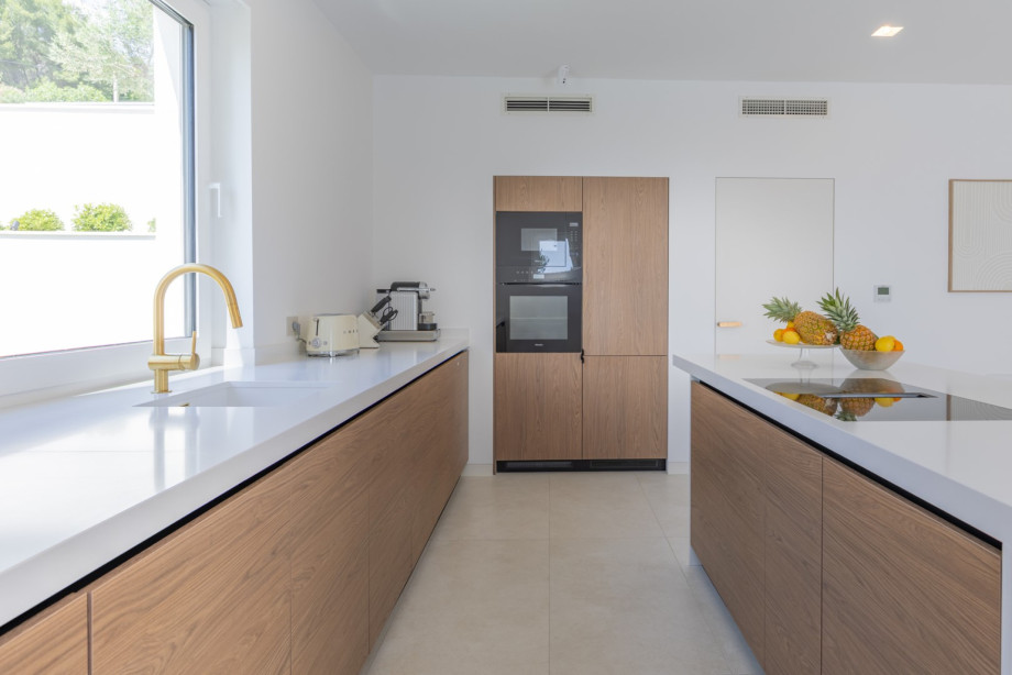 Das klare Design, die warmen Holzoberflächen und das natürliche Licht schaffen einen eleganten und funktionalen Raum zum Zubereiten von Mahlzeiten und zum Beisammensein.