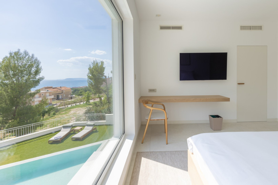 Helles Schlafzimmer mit großem Fenster mit Blick auf die Poolterrasse und freiem Blick auf Split und die Inseln