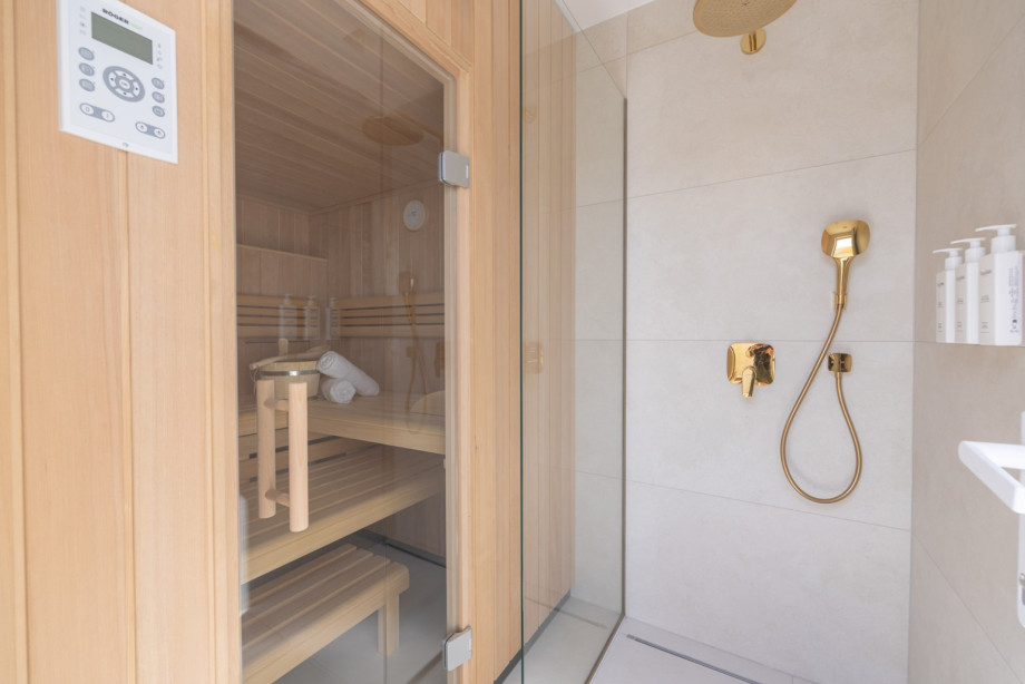 Wellnessbadezimmer mit privater Sauna, begehbarer Dusche, goldfarbenen Armaturen und preisgekrönter Natura Bissé Kosmetik.