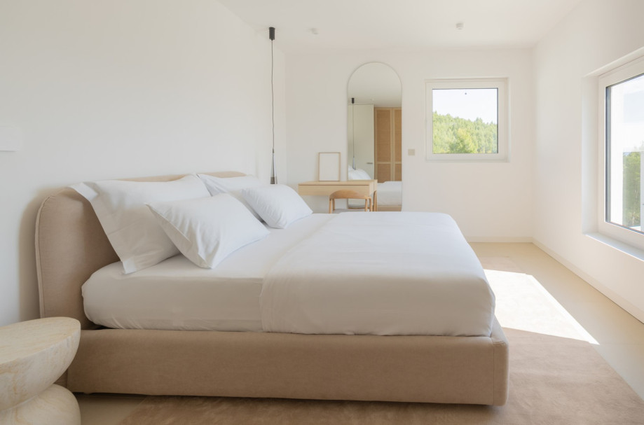 Elegant bedroom with a soft upholstered bed, minimalist design, and warm neutral tones