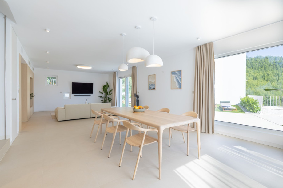 Bright dining area with renowned designer furniture from Artisan, soft pendant lighting, and an open connection to the living room
