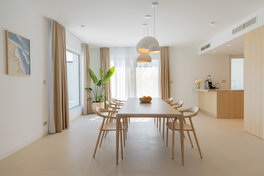 Large windows overlooking Mediterranean greenery and the open-plan layout create a relaxed space for shared meals