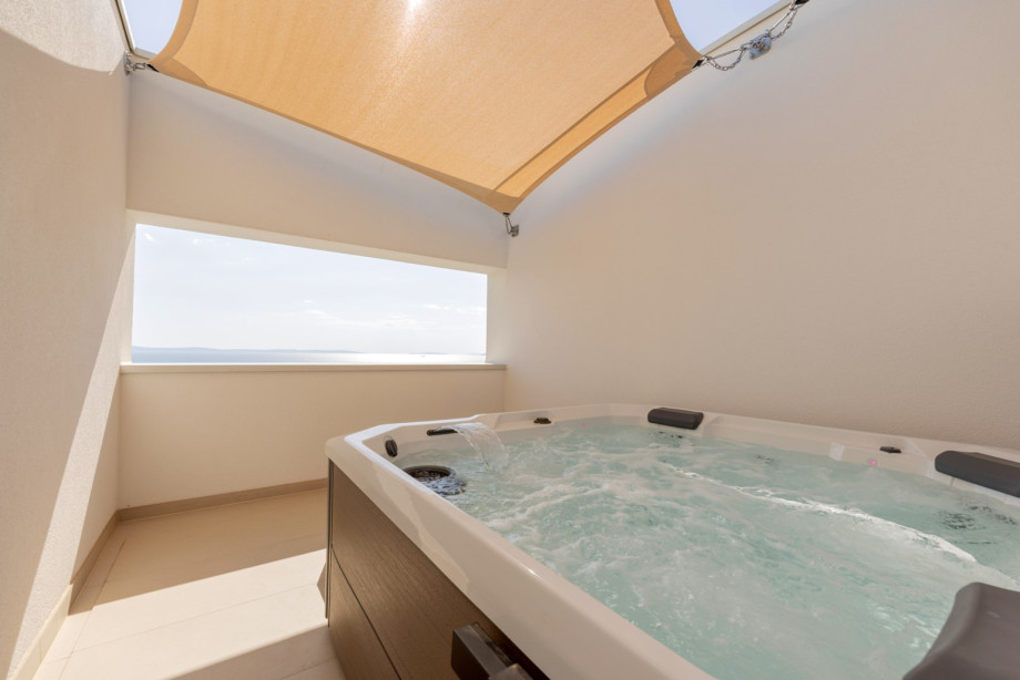 Rooftop wellness terrace with a private jacuzzi, shaded lounge area, and open views of the sea, Split, and the islands