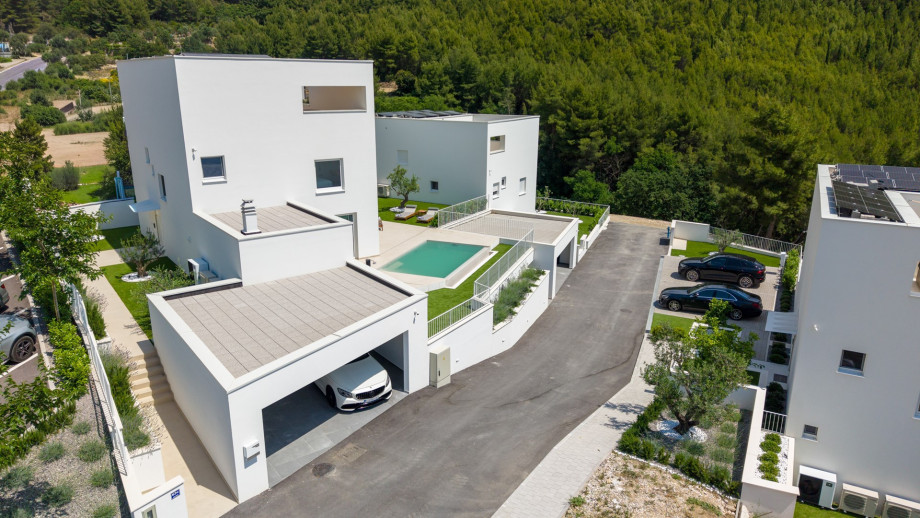 Aerial view of the private villa with a pool, landscaped terrace, covered parking, and Mediterranean greenery