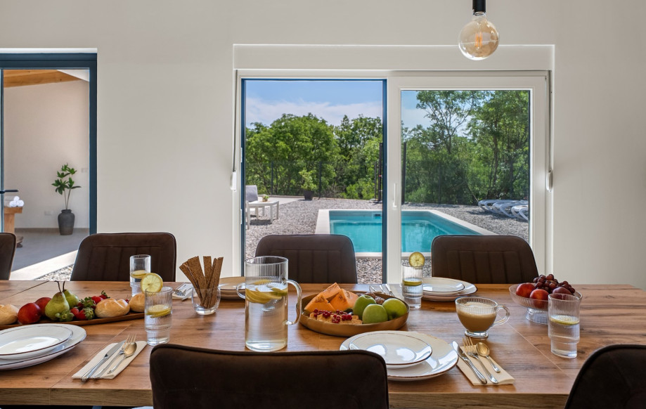 Behind sliding doors, a fully equipped summer kitchen awaits, featuring a dining table.