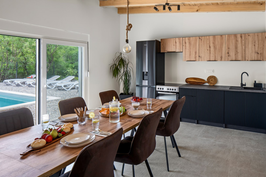 A fully equipped summer kitchen awaits, featuring a dining table, lounge corner with a flat-screen TV, air conditioning.