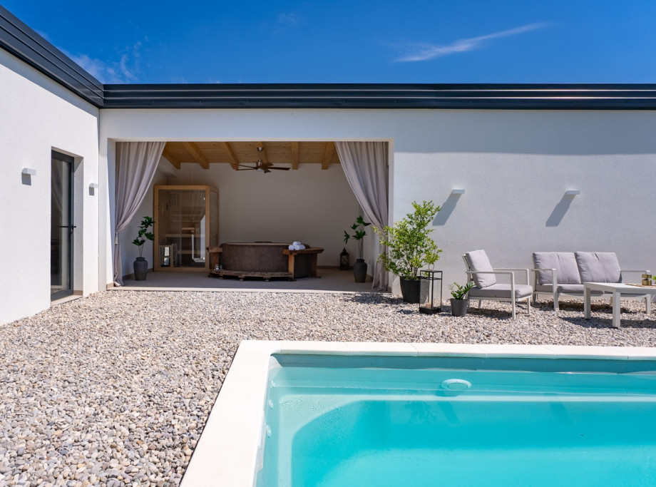 Surrounding the pool is a spacious sun deck covered with pebbles, furnished with eight deck chairs, a lounge corner
