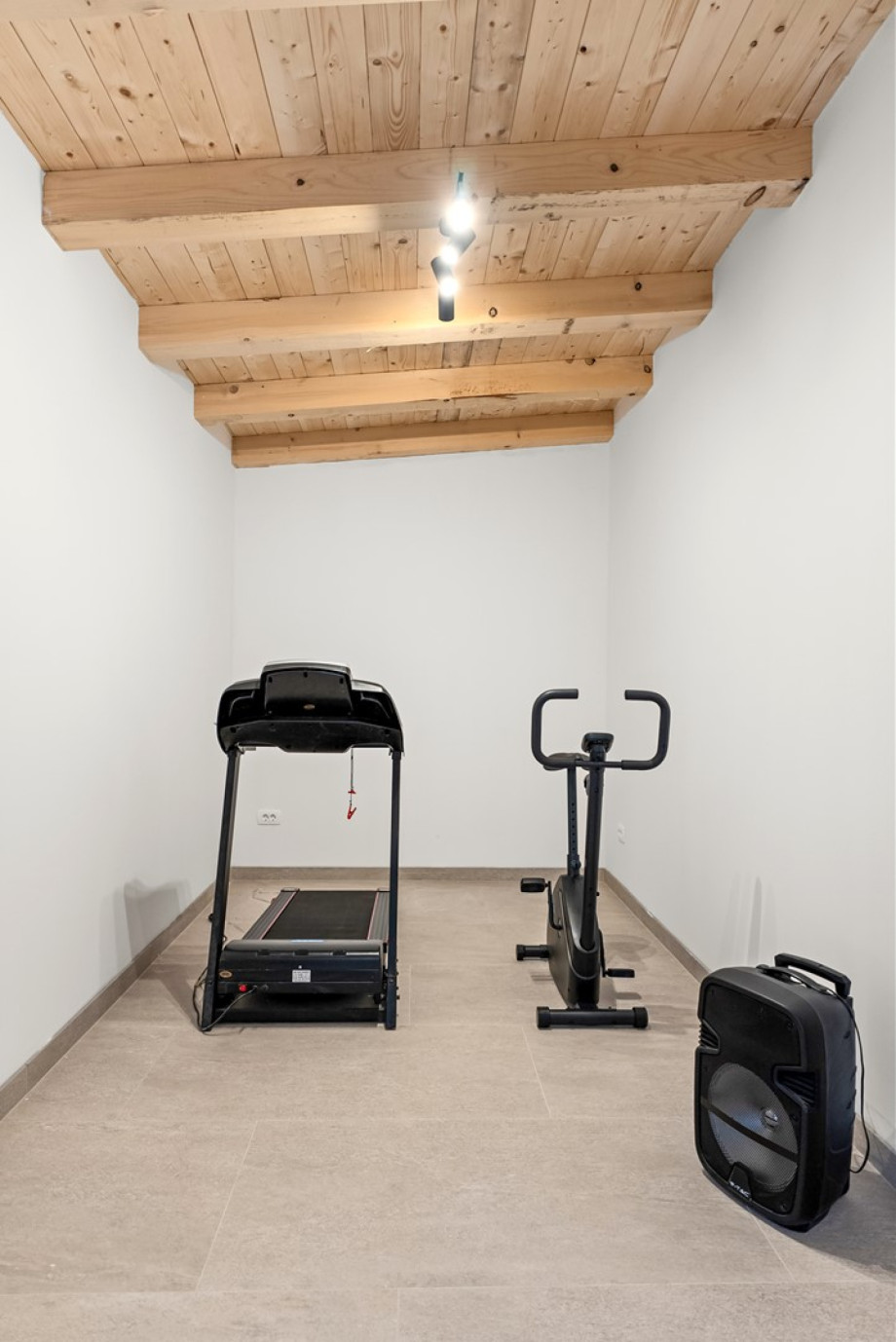 Gym equipped with a treadmill and exercise bike, along with a nearby toilet.