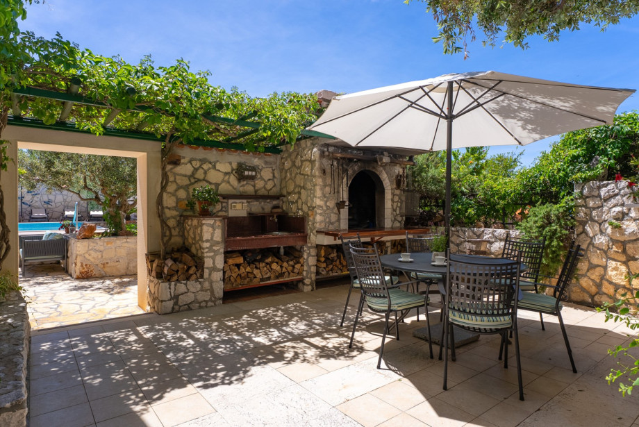 Traditional charcoal and wood barbecue located next to the pool area.