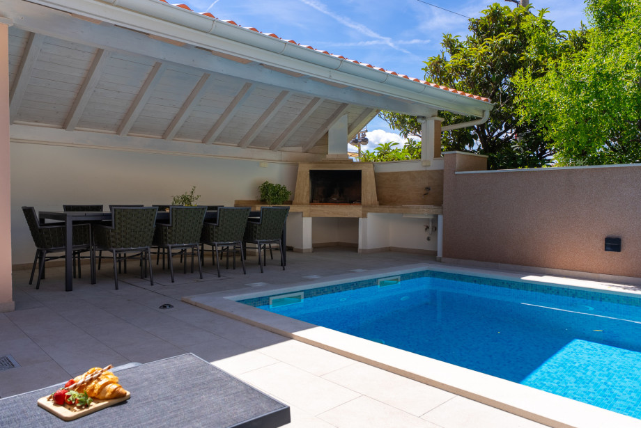 Outdoor covered dining area with a barbecue, perfect for a family gathering