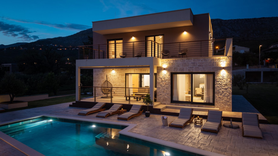 Villa Agrosa at night: a stylish 4-bedroom retreat with a 30 sqm private pool and glowing stone architecture.