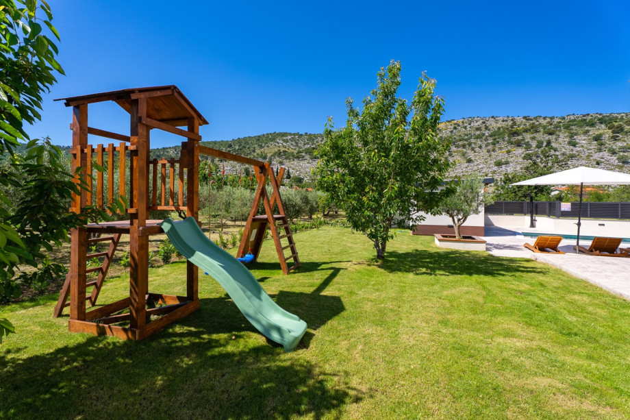 The villa features a dedicated children’s frame with a swing and a slide for outdoor play.