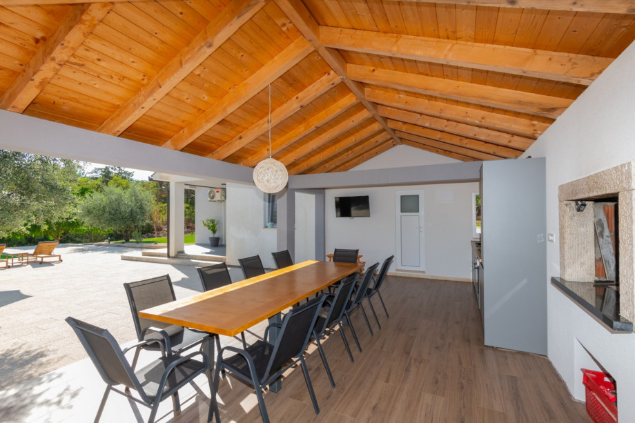 Sommerküche mit Grillbereich für Holz oder Kohle und einem Essplatz im Freien.