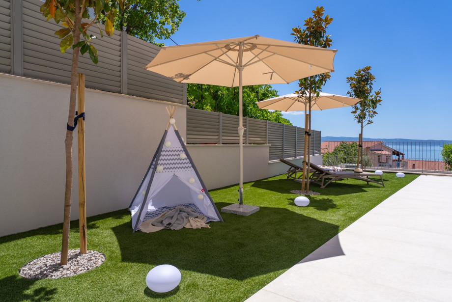 Kids' corner on the lawn features a play tent and a selection of toys.