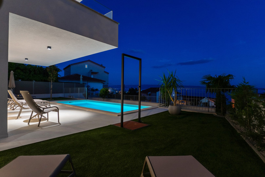 A Zen outdoor shower with a matte black frame is located right by the pool.