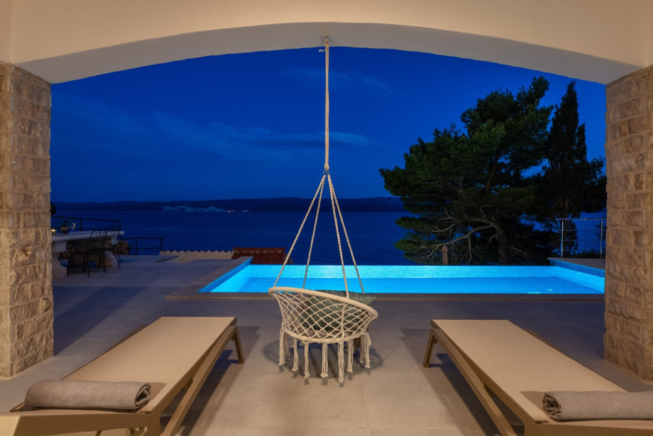 Relaxation setup by the pool includes lounge chairs and a cozy swing chair.