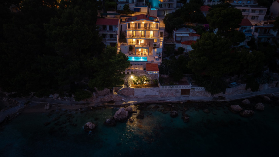 Outdoor stone staircase leads from the lower deck directly down to the pebble beach.