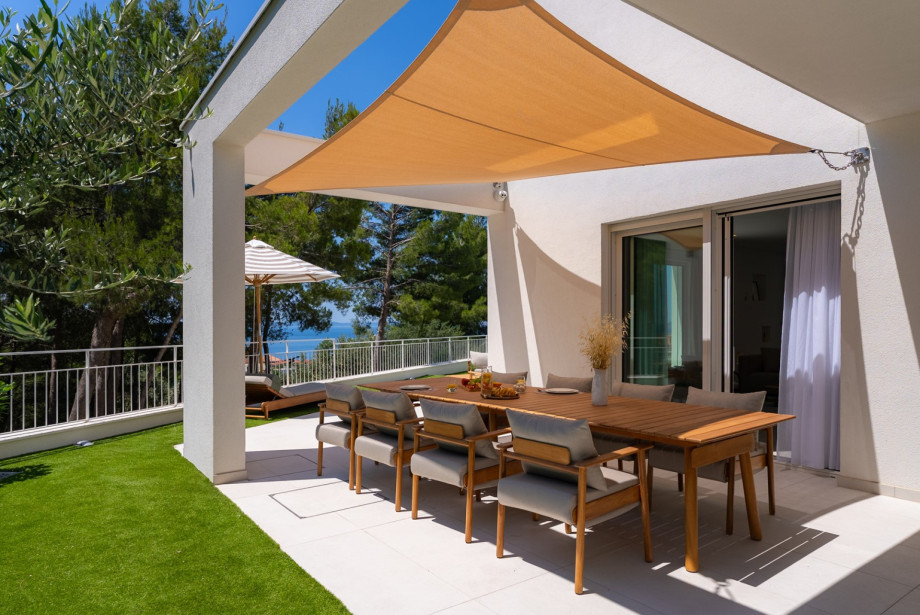 Large glass doors bring in natural light and offer relaxing views of the pool, greenery, and sea