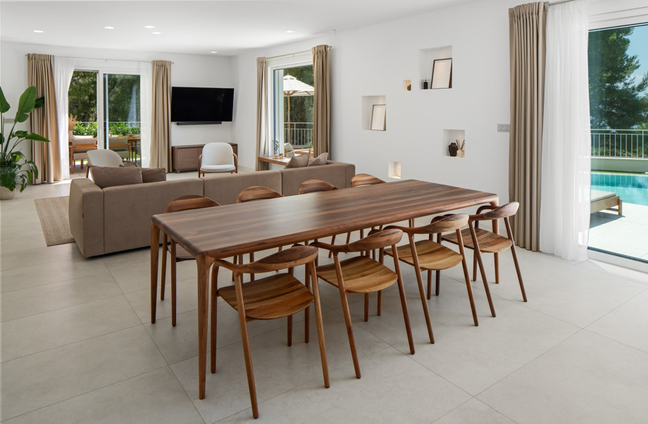 Elegant dining area featuring Artisan's furniture, a spacious wooden table, and direct access to the pool terrace