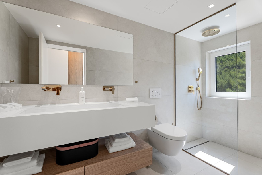 An en-suite bathroom with a shower, double sink, and a toilet
