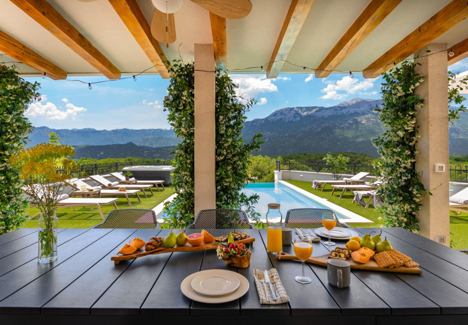 For outdoor dining, there is a covered area with a barbecue, an outdoor bar with a fridge and ice maker, and a dining table that seats eight