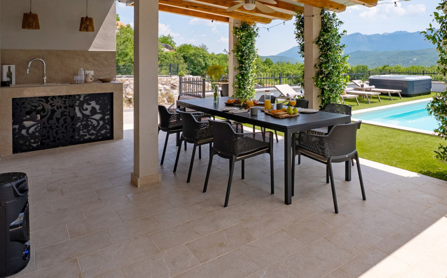 For outdoor dining, there is a covered area with a barbecue, an outdoor bar with a fridge and ice maker, and a dining table that seats eight