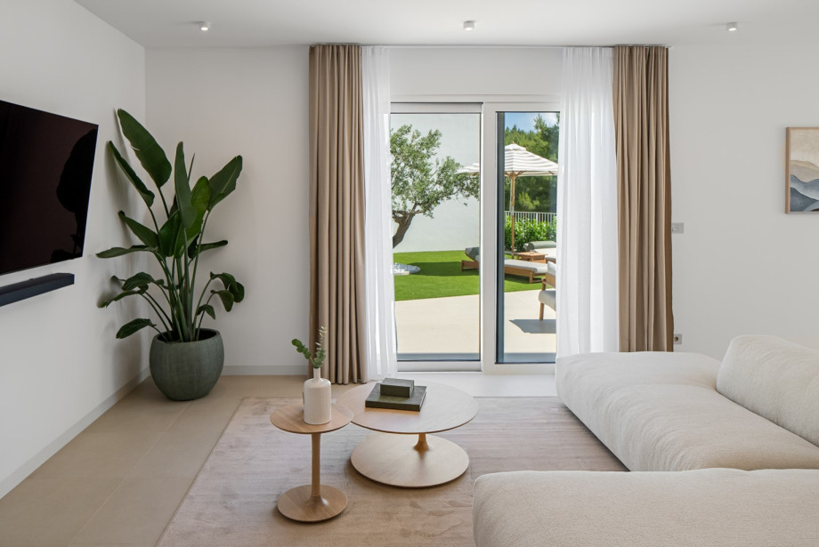 Helles Wohnzimmer mit einem weichen Designersofa der renommierten kroatischen Möbelmarke Prostoria, natürlichen Texturen und direktem Zugang zur Außenterrasse