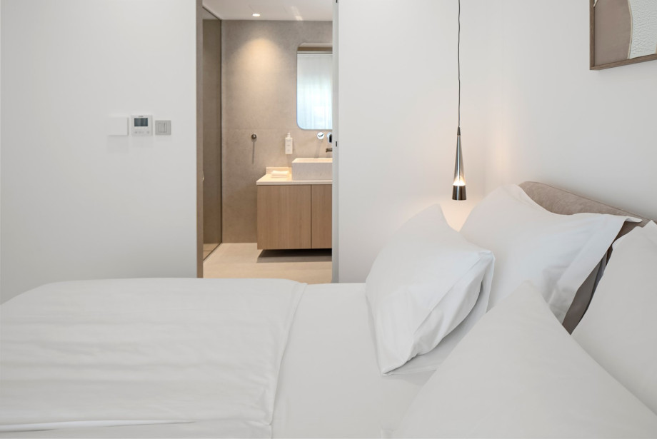 Elegantes Schlafzimmer mit weich gepolstertem Bett, minimalistischem Design und warmen, neutralen Farbtönen