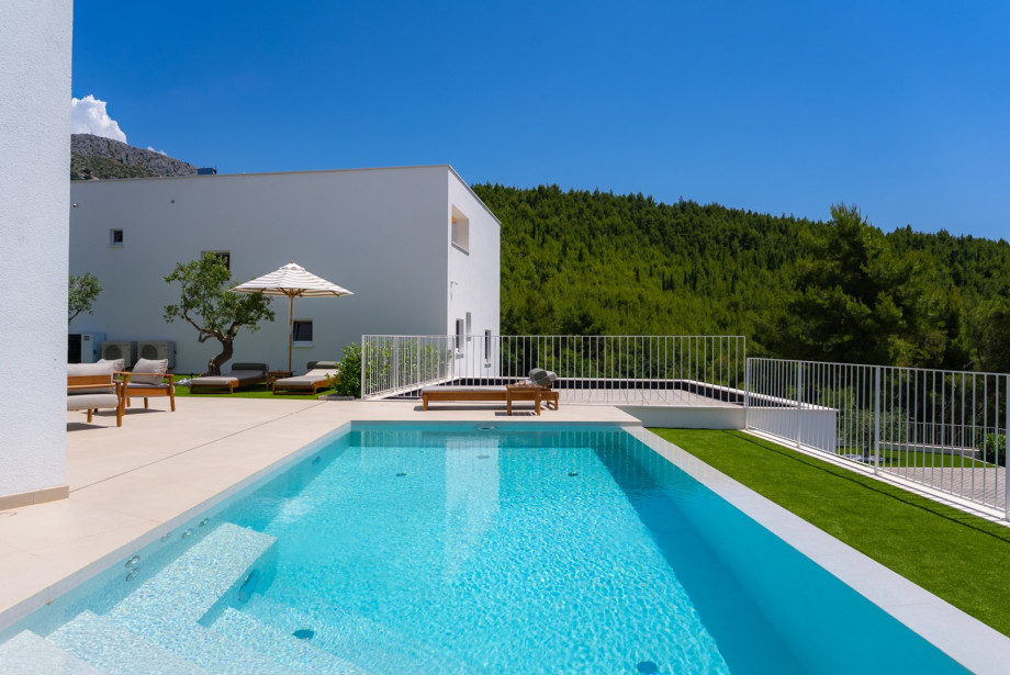 Ein beheizter/gekühlter 23 m2 großer Infinity-Pool mit Hydromassage und eine großzügige Rasenfläche mit Liegestühlen, perfekt zum Entspannen