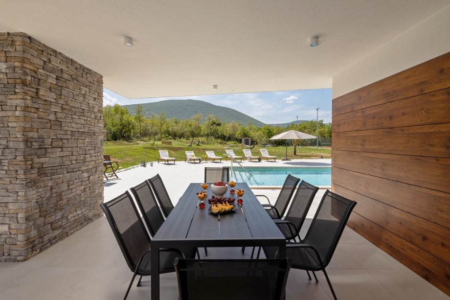 There is a covered outdoor dining area for 8 people with a gas barbecue