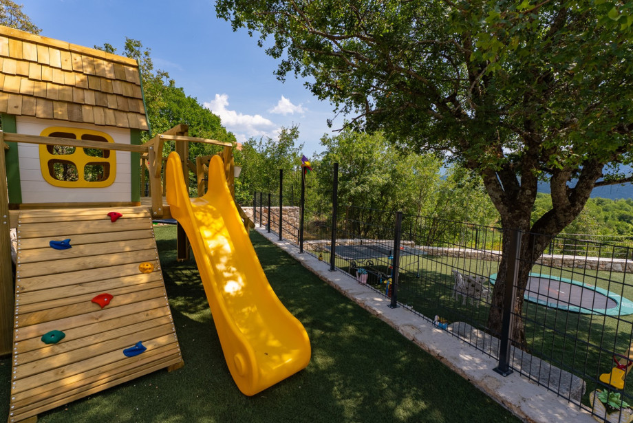 A fenced grass playground that provides a safe space for children, making it an ideal spot for younger family members to play.