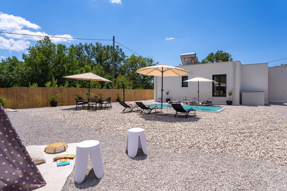The outdoor area features a private swimming pool (6m x 3.2m), perfect for a refreshing dip, along with a sun deck area covered with beach pebbles