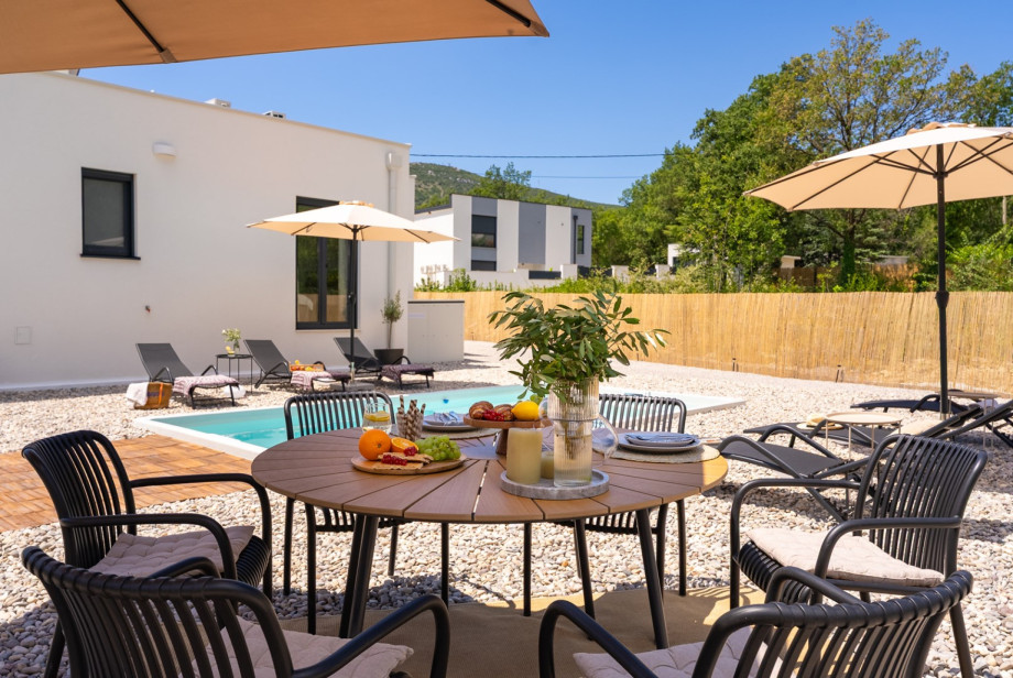 The covered dining area comfortably seats 6 people and is accompanied by a charcoal barbecue