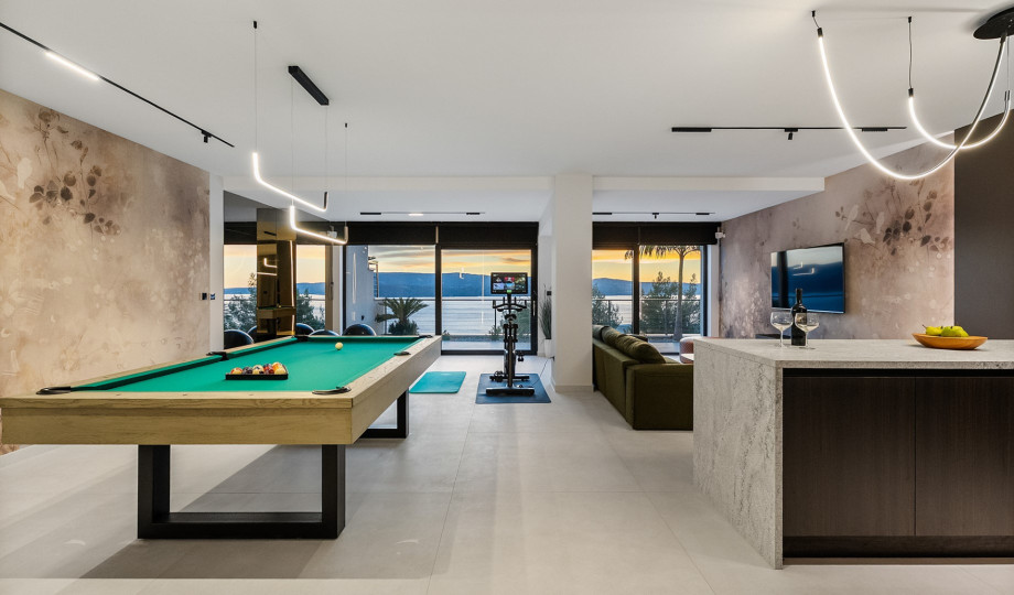 The indoor entertainment zone on the spa level features a billiard table, a kitchenette, and an adjacent gym area.
