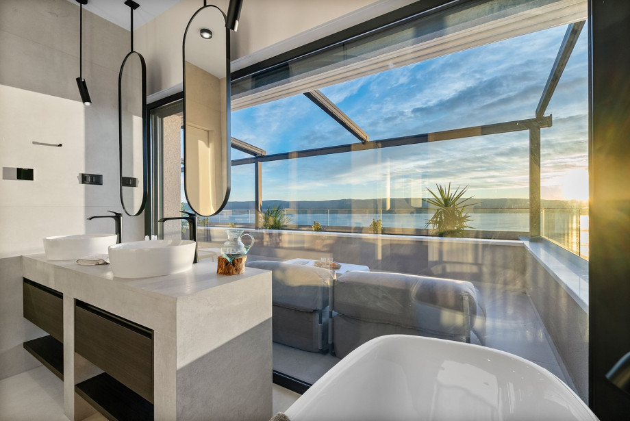 The en-suite bathroom of the master bedroom includes double sinks and views out to the private terrace with the hot tub.
