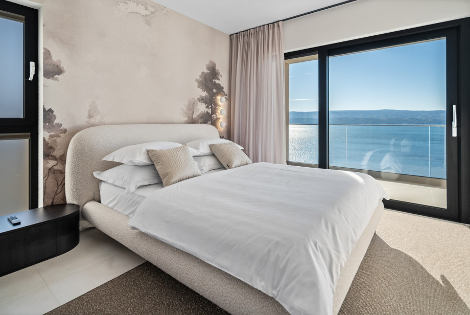 This room features a queen-size bed and a glass sliding door that provides spectacular sea views.