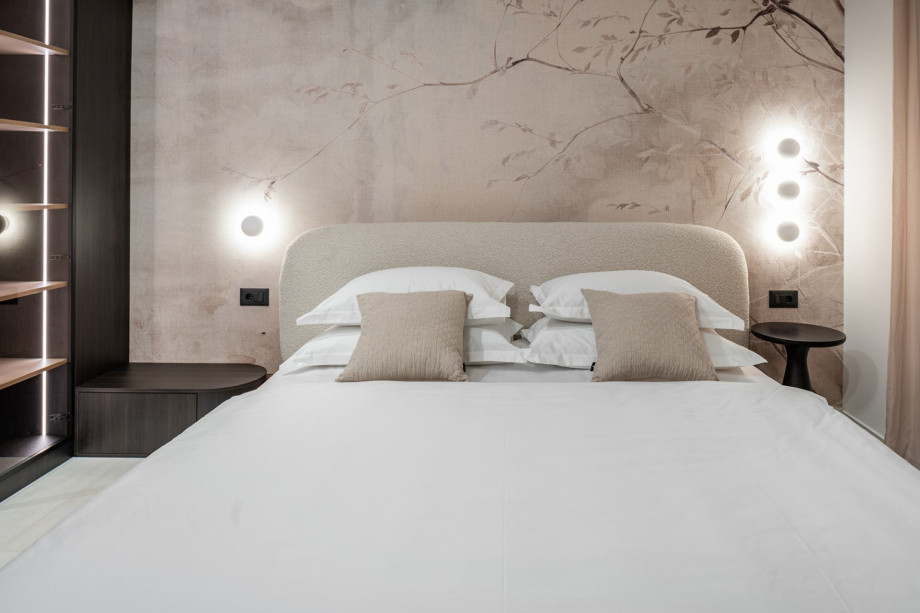 This room features a king-sized bed set against a background of beautiful, stylised wall art and subtle lighting.