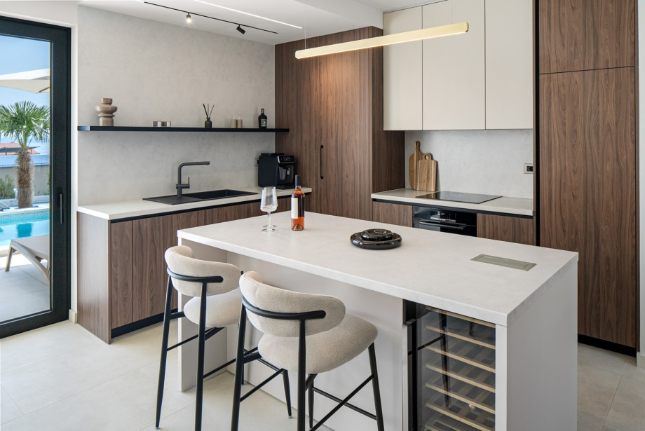 The fully stocked kitchen is equipped with modern appliances, including a microwave, coffee capsule machine, and all the essentials for a seamless stay