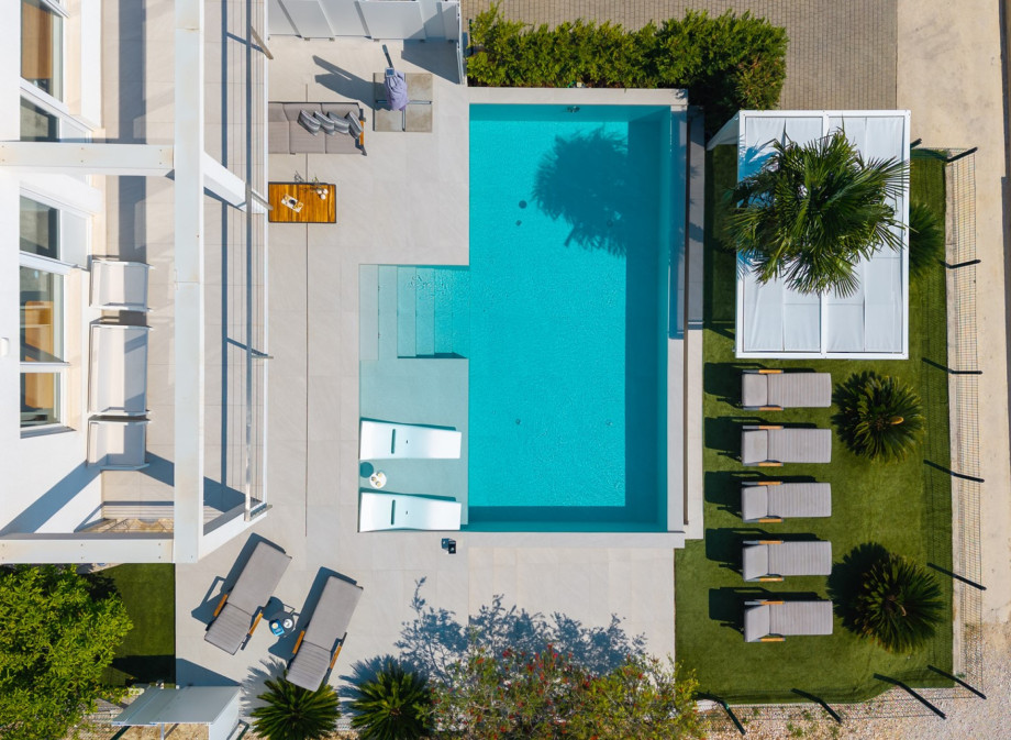 The centrepiece is the private heated pool, surrounded by sun deck chairs and shaded by parasols