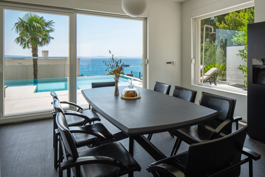 Dining table, a glass door toward the pool on one side, and an outdoor dining area on the other side.