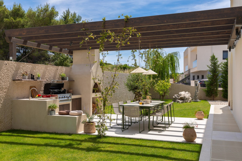 The shaded dining terrace with a gas and wood/charcoal barbecue is perfectly positioned for effortless alfresco meals