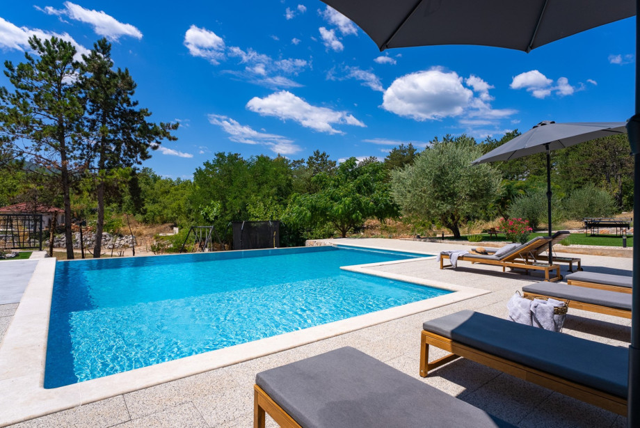 The sun deck area is furnished with comfortable loungers and umbrellas surrounding the infinity pool.