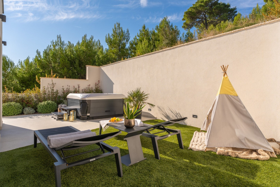 Die Terrasse verfügt über einen Whirlpool, zwei Liegestühle, zwei Stühle und einen Kunstrasenbereich mit einem Spielbereich für Ihre Kleinen
