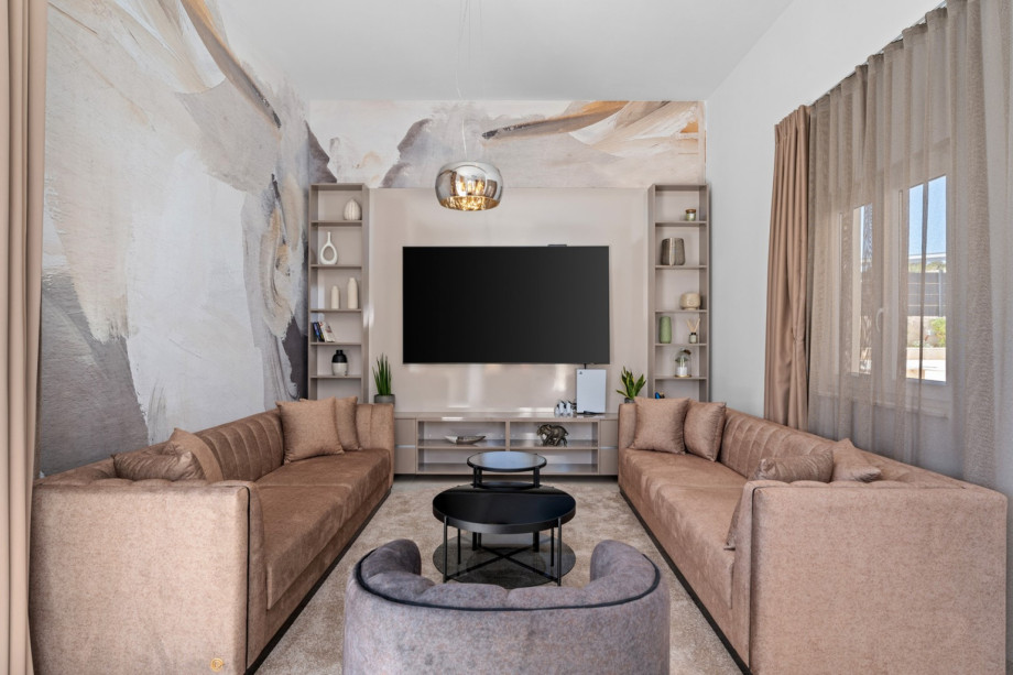A living room with two sofas, a TV, PlayStation 5, A/C, and free WiFi.