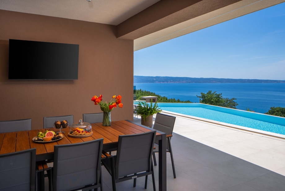 Covered outdoor dining area with a table that accommodates up to 10 guests.