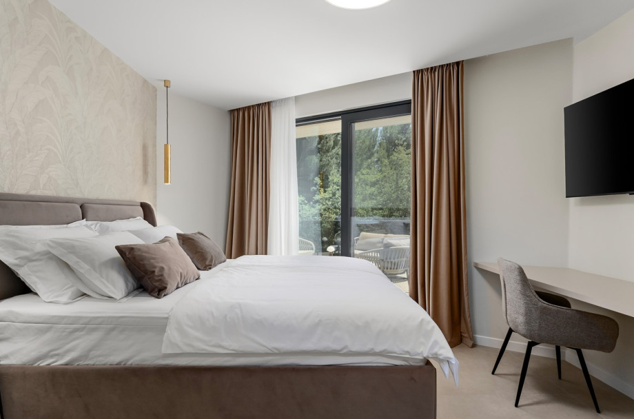 Elegant bedroom layout featuring a king-size bed and a flat-screen TV.