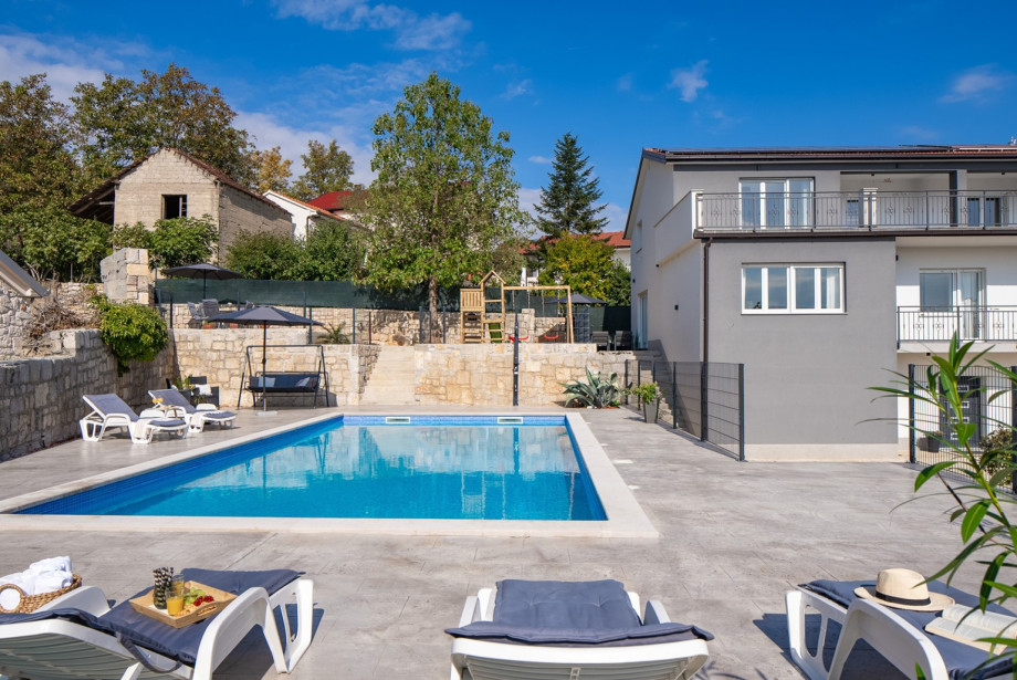 Enjoy the private 50sqm pool area with comfortable sun loungers, set against the backdrop of the modern main house and the stone-walled elevated playground.