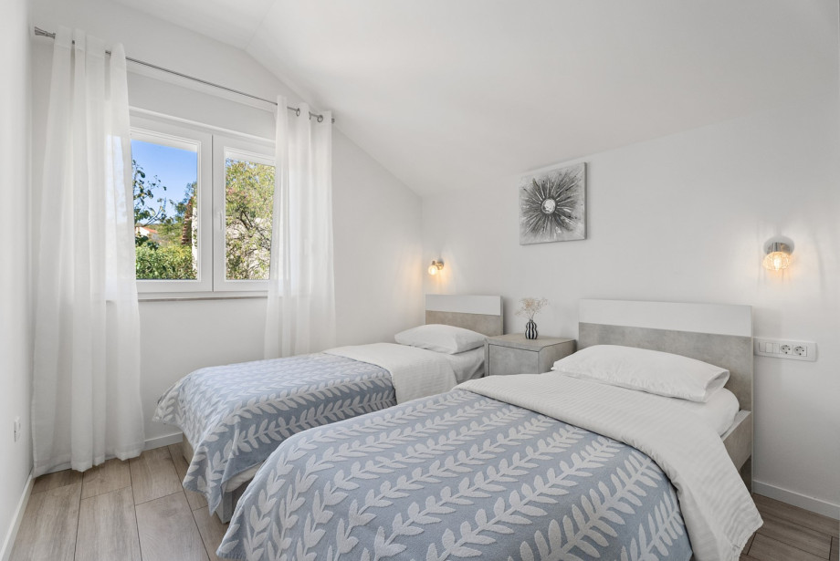 Bedroom 5 on the upper floor features cosy twin beds (80cm x 190cm), air conditioning, and views of the neighbourhood.